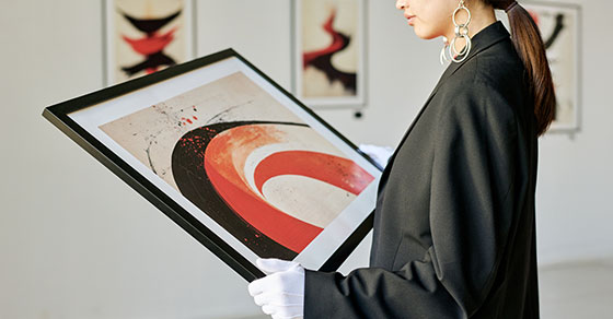 Woman looking down at framed artwork that she is holding
